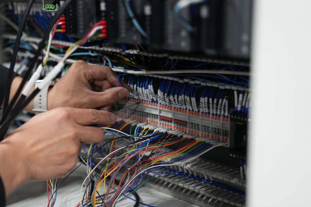 Hands working on terminal wiring in an electrical control cabinet