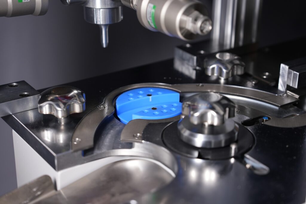 Close-up of a machine station with a blue fixture and metal rotary plate