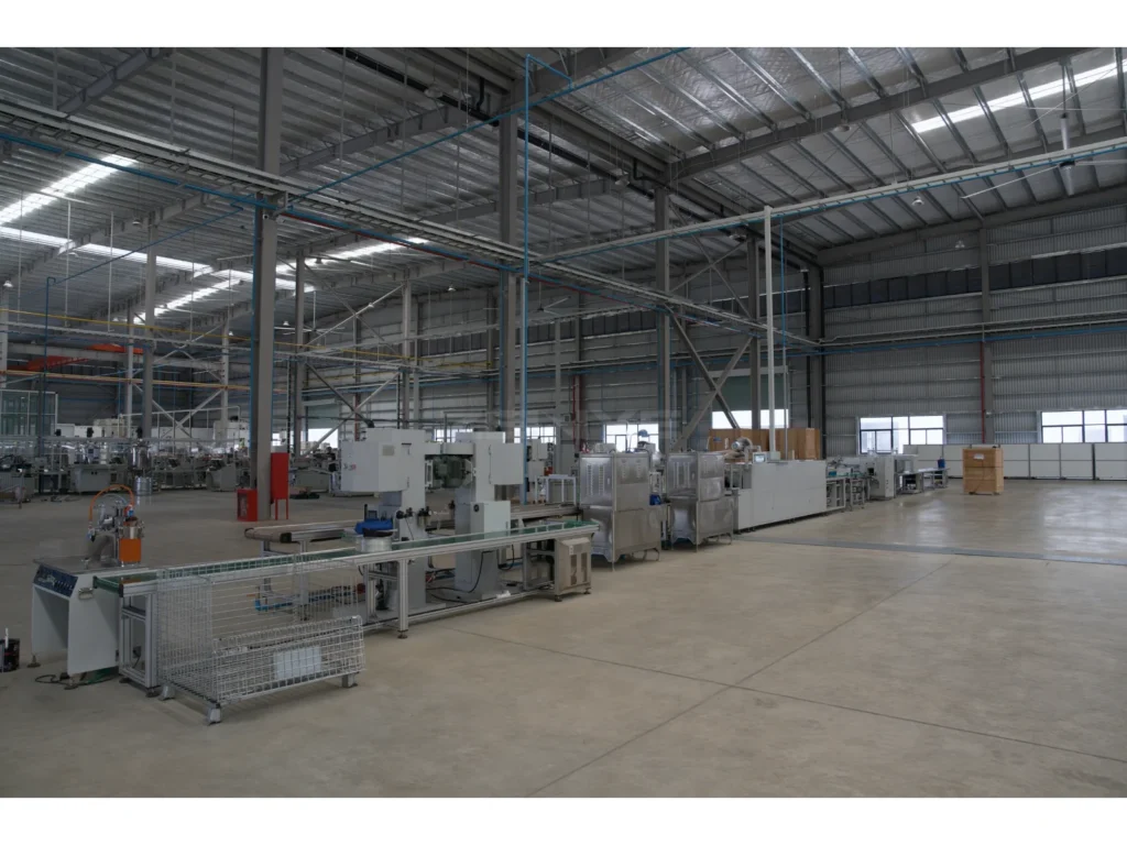 Machinery and conveyors arranged alongside an open aisle inside a factory.