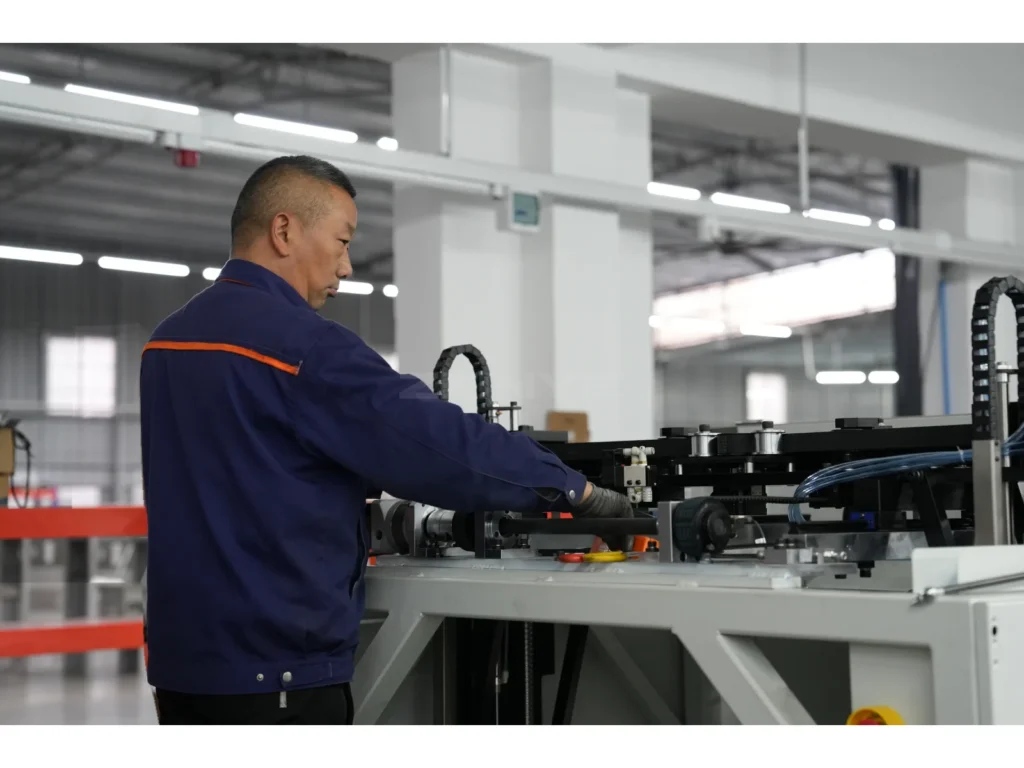 A worker in a blue uniform working beside industrial equipment.