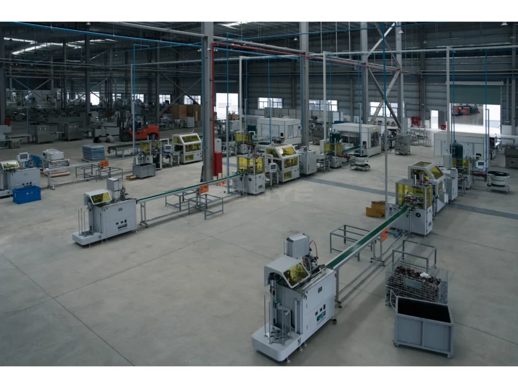 A wide factory view showing machinery, conveyors, columns and circulation space.
