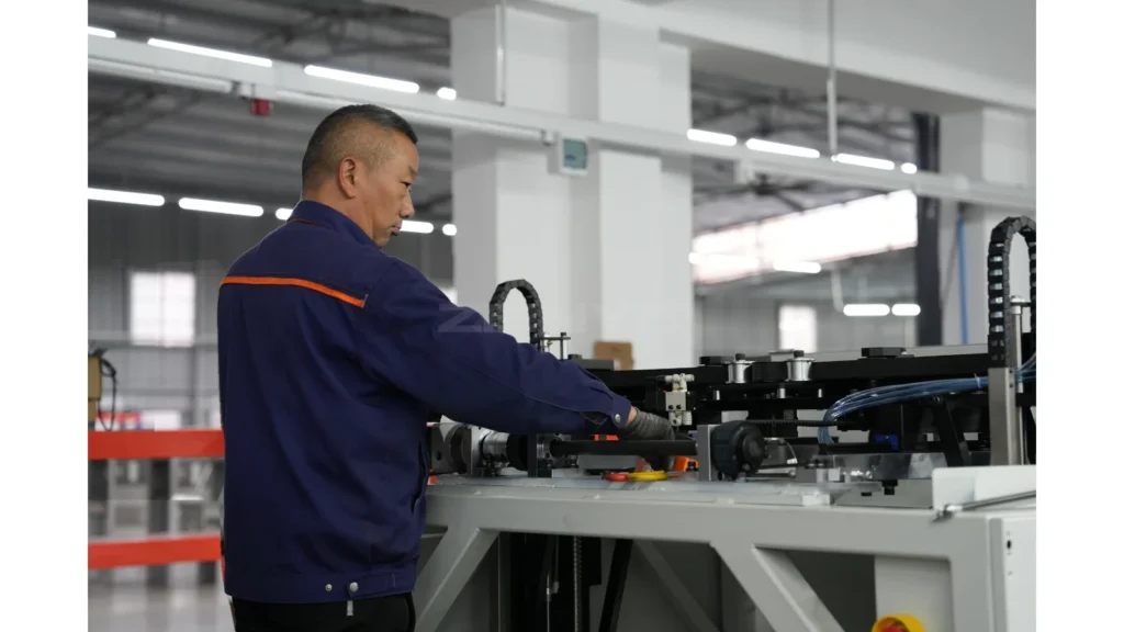 A worker in a blue uniform working beside industrial equipment.